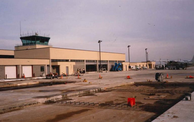 Image of a runway being constructed with planes and an airport center in the background.